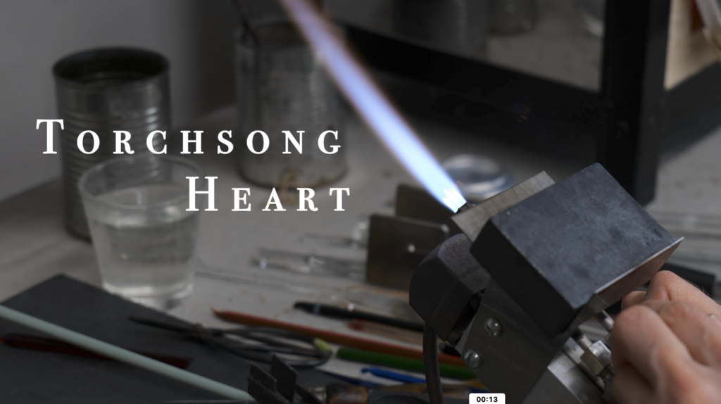 a lampworking torch flame with the text "Torchsong Heart"